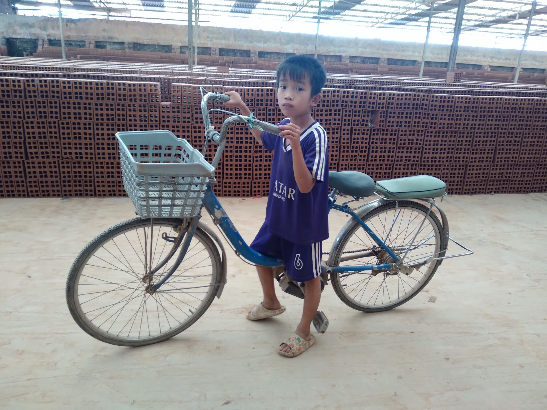 Cậu học trò nhỏ Nguyễn Minh Tiến không ngủ trưa mà miệt mài đạp xe vòng vèo trong sân phơi gạch.