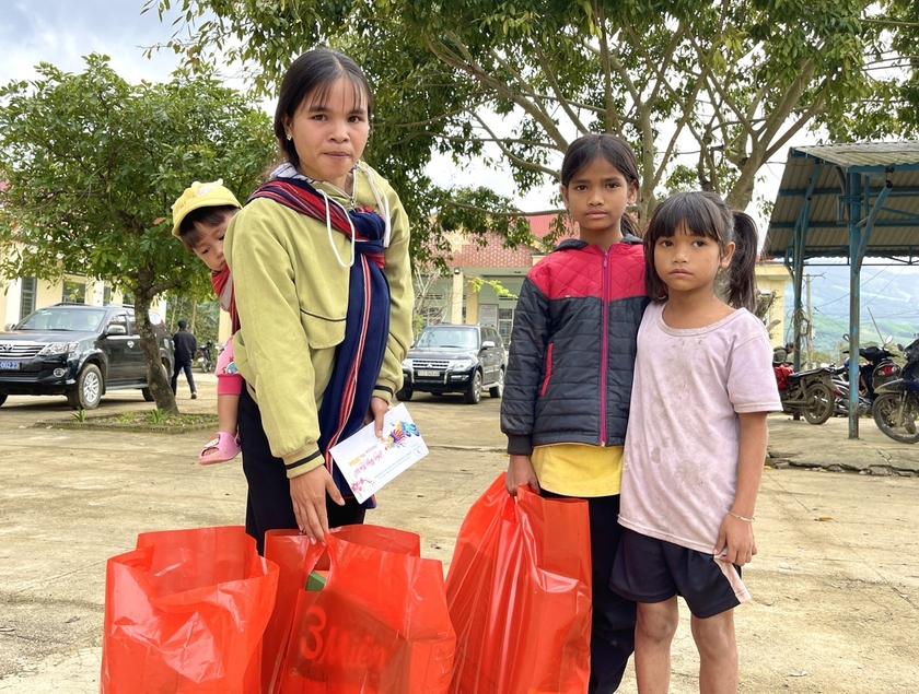 Chị Đinh Thị Dơh-một trong số hộ nghèo của làng Mèo (xã Đak Pling) địu theo con nhỏ có mặt từ rất sớm để nhận phần quà Tết nghĩa tình. Ảnh: Minh Phương